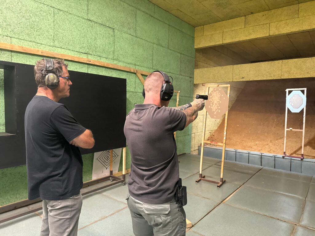A shield tactical shooting instructor supervising a student