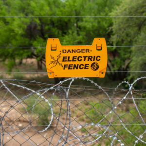 A yellow warning sign on an electric fence