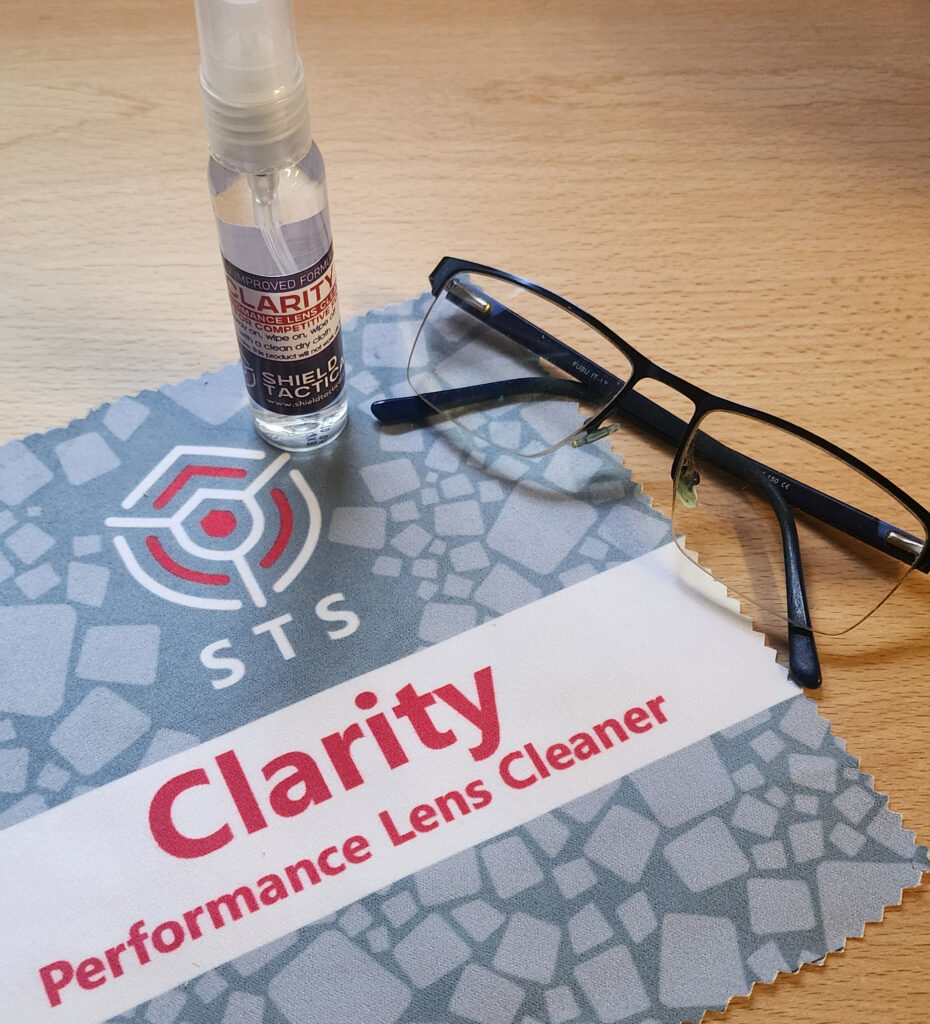 An image showing Clarity Performance lens cleaner with a pair of glasses and a microfibre cleaning cloth